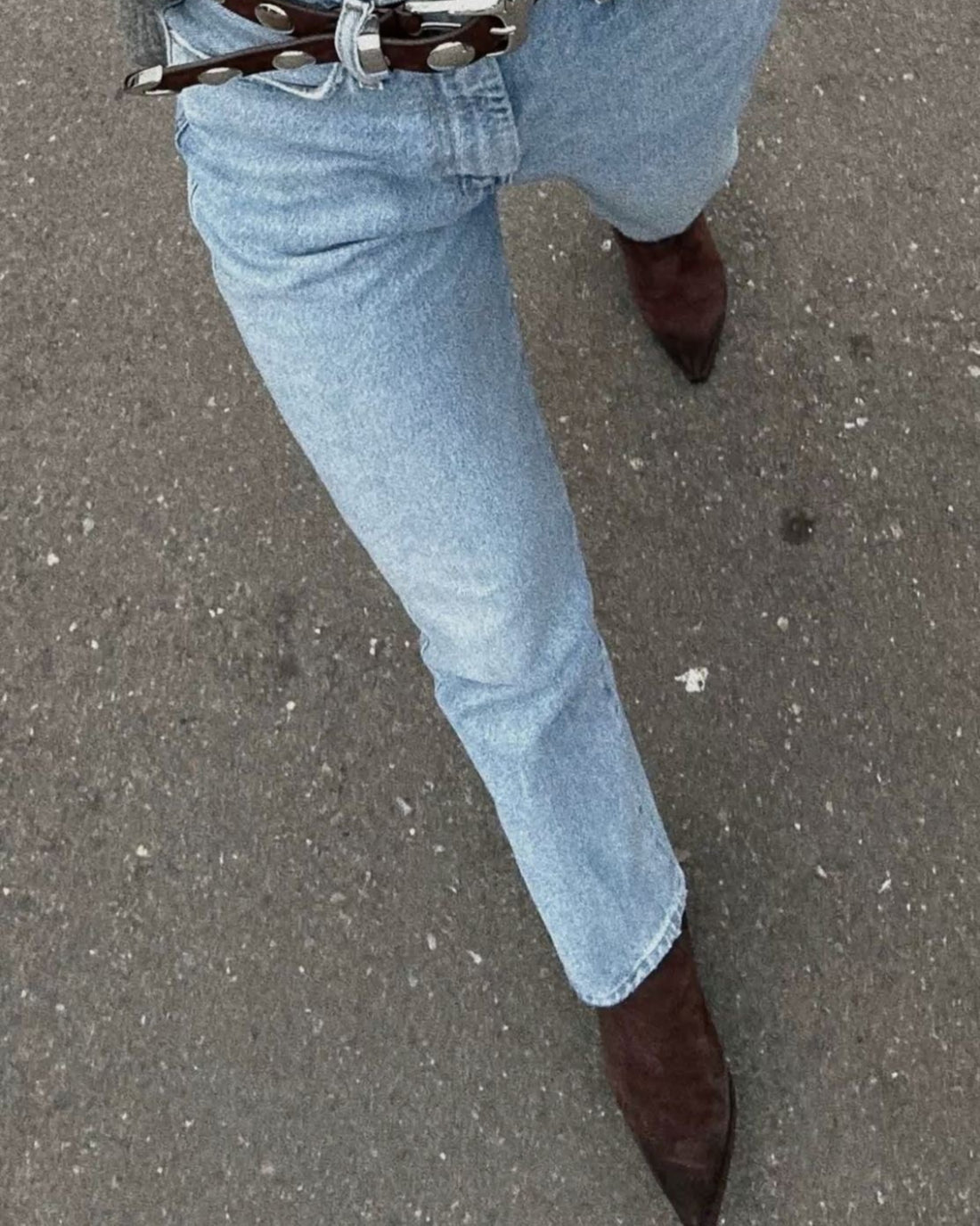 a woman wearing jeans and boots walking
