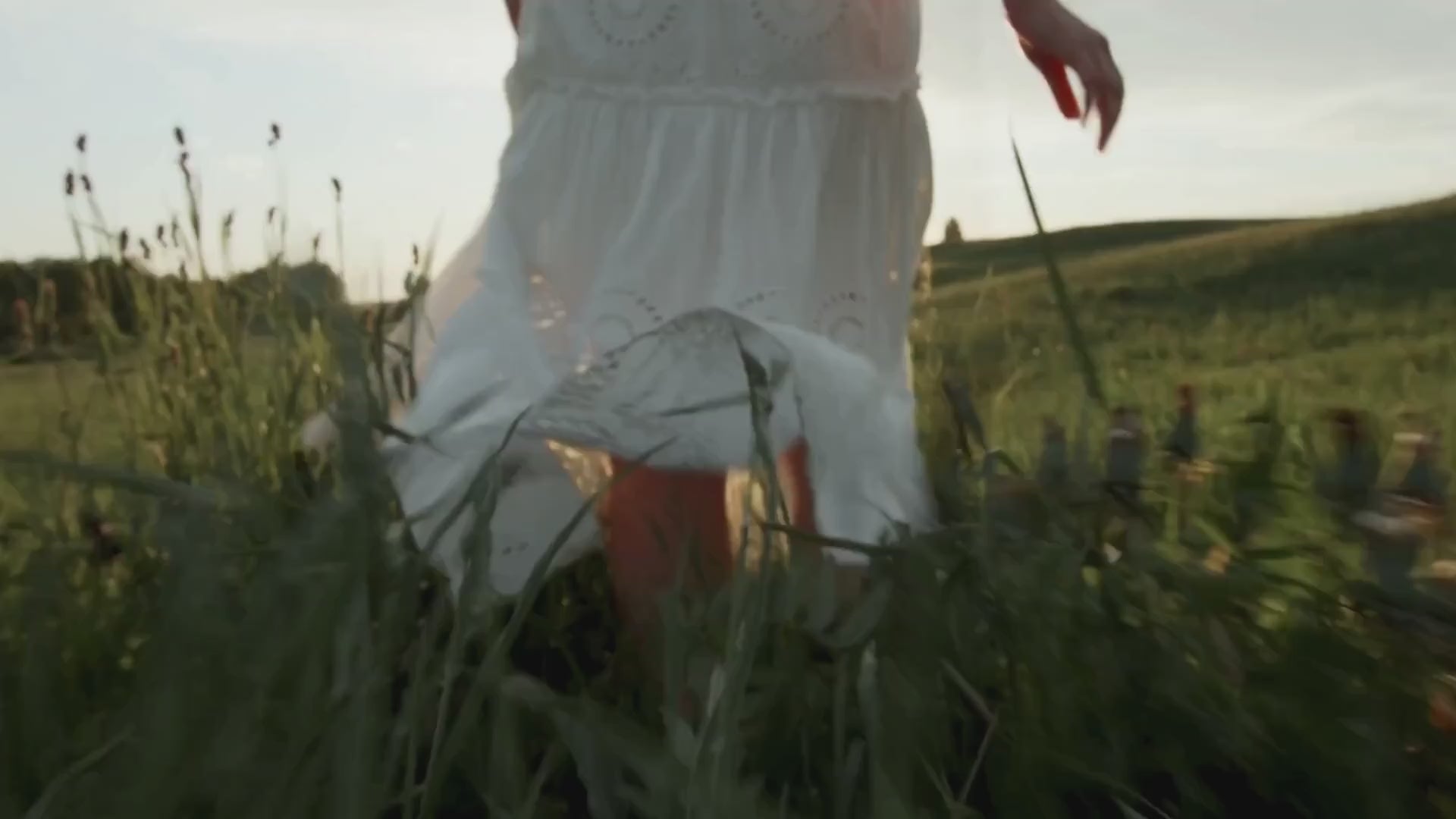 A video of girl running through grass, man walking through forest, woman standing by the lake, a man's feet on a boat dock